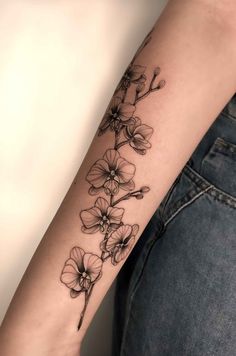 a woman's arm with flowers tattooed on the left side of her arm, in black and white