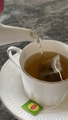 tea being poured into a white cup on a saucer