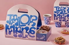 a table topped with donuts covered in frosting and sprinkles next to two paper cups