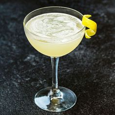 a martini glass with a lemon garnish on the rim, sitting on a black table