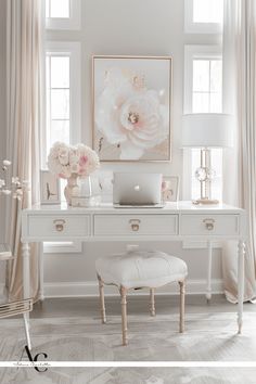 a white desk with flowers and a laptop on it