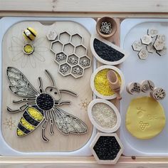 a wooden tray with bees and honeycombs on it, next to some spoons