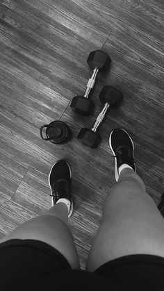 black and white photograph of person's legs with gym equipment on the floor behind them