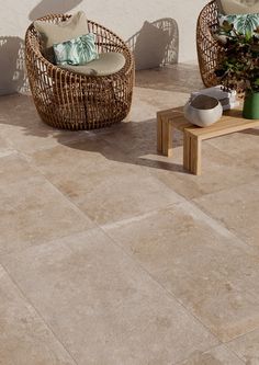 two wicker chairs sitting next to each other on top of a stone flooring