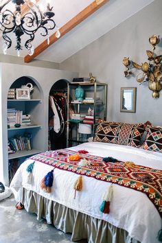 a room with a bed, bookshelf and various items on the shelves in it