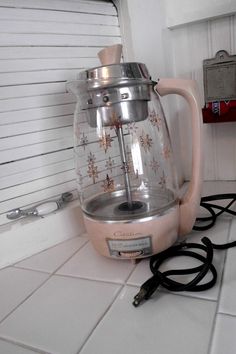 an electric tea kettle sitting on top of a white tile floor next to a heater