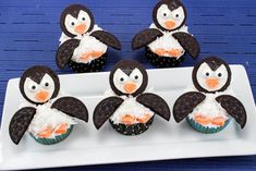 four cupcakes decorated like penguins on a plate