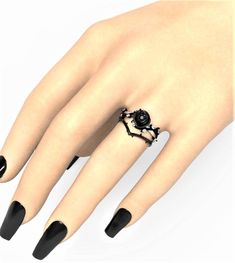 a woman's hand with black nail polish and an ornate ring on her finger