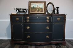 an antique dresser has been painted black with gold trimmings and is next to a painting on the wall