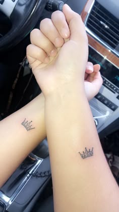 two people with tattoos on their arms holding each other's hands in a car