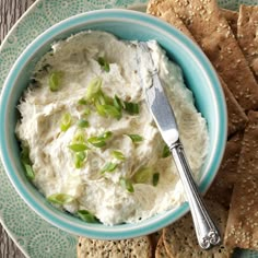 a blue bowl filled with hummus and crackers