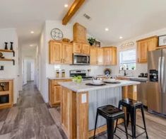 a large kitchen with wooden cabinets and stainless steel appliances, along with two stools