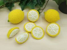 crocheted lemons are arranged on a table next to some green leaves and flowers