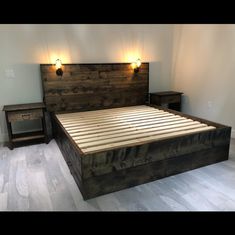 a bed with wooden headboard and night lights on the wall next to two nightstands