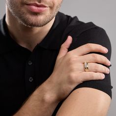 a man wearing a black polo shirt with a gold ring on his left hand and a white diamond in the middle