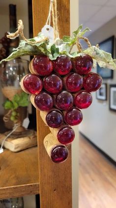 a bunch of grapes hanging from a wooden pole in a room with wood flooring