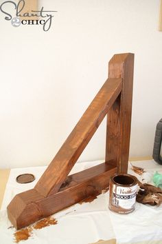 a wooden frame sitting on top of a table next to a paint can and brush