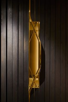 a wall light that is on the side of a wooden paneled wall in a dark room