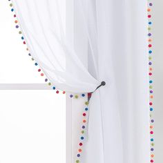 the curtain is decorated with multicolored polka dot trim and tassels on it