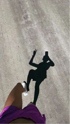 a person standing in the middle of a street with their shadow on the ground