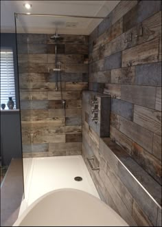 a bath tub sitting next to a wooden wall in a bathroom with a walk in shower