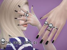 a woman's hands with black and white nail polishes on her nails, holding several skull rings