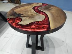 a wooden table with red and black paint on it's top, sitting in a room