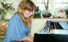 a woman is playing the piano in her living room