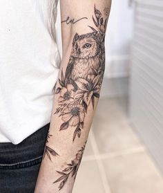 an owl and flowers tattoo on the arm