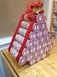 a christmas tree made out of wrapping paper and wrapped in red ribbon with numbers on it