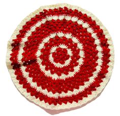 a red and white crocheted dishcloth with a spiral design in the center