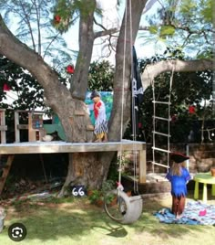 a woman in a blue dress standing next to a tree with an upside down swing