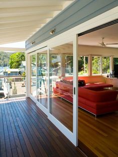 a large deck with red couches and sliding glass doors leading to an outdoor living area