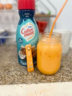 an orange smoothie in a mason jar next to a carton of coffee mate