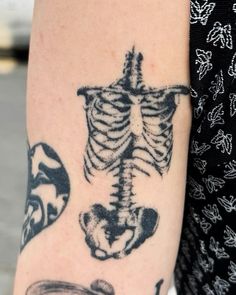 a woman's arm with a skeleton tattoo on it, and a clock in the background