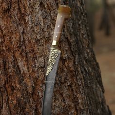 a knife stuck in the bark of a tree with an intricate carving on it's blade