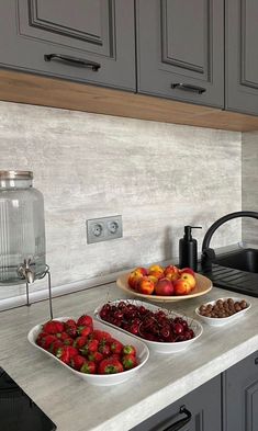 two bowls of fruit are sitting on the kitchen counter