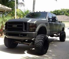 a large gray truck parked on the side of a road next to a palm tree