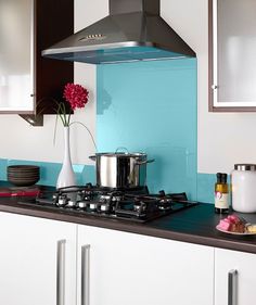 a stove top oven sitting inside of a kitchen next to white cupboards and drawers