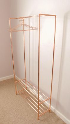 a metal rack with clothes hanging on it in a corner next to a white wall