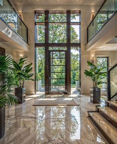 a large foyer with marble floors and high windows, surrounded by potted greenery