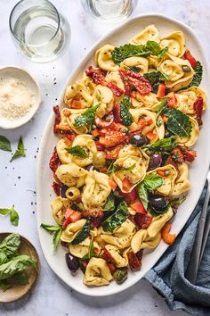 a white platter filled with pasta and veggies on top of a table