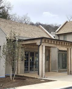 the front of a house with an attached patio and covered in wood shinnings