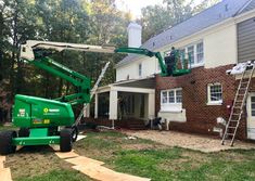 two men are working on the back of a house with a green truck in front of it