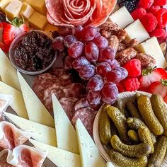 an assortment of cheeses, crackers and fruit on a platter with flowers