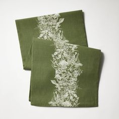 two green napkins with white flowers on them