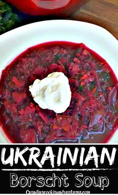 a white plate topped with soup next to a red container filled with sour cream and vegetables