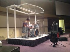 a man is playing drums on stage in a room with purple carpeted flooring