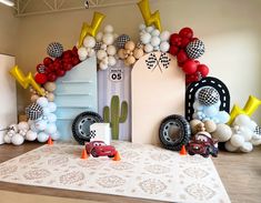 balloons and cars are on the floor in front of an entrance to a race car themed birthday party