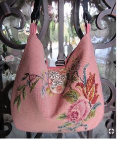 a pink purse with flowers on it hanging from a wrought iron gate, in front of a window